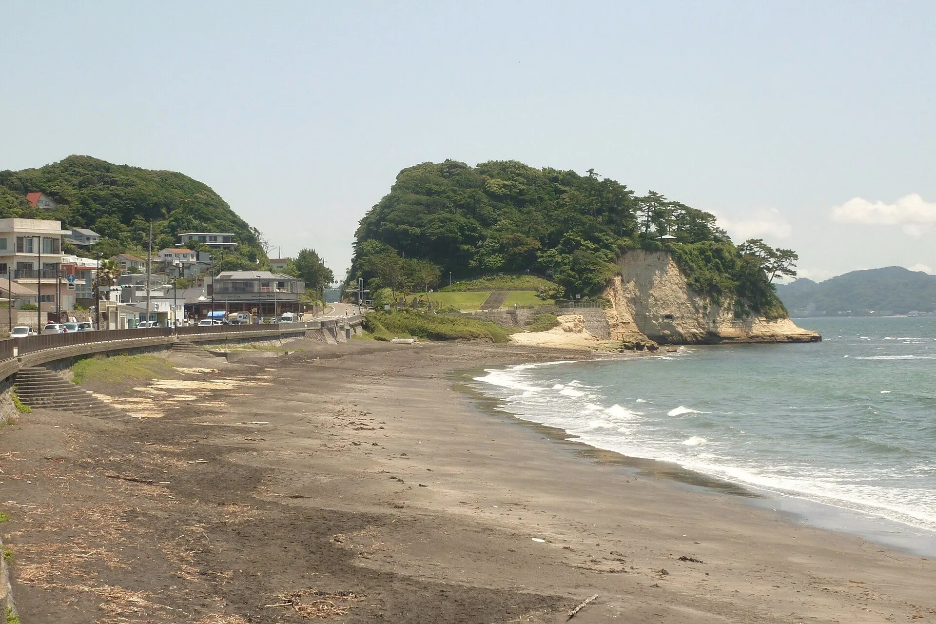砂浜越しに見た稲村ヶ崎。緑に覆われた岬が海へ突き出している