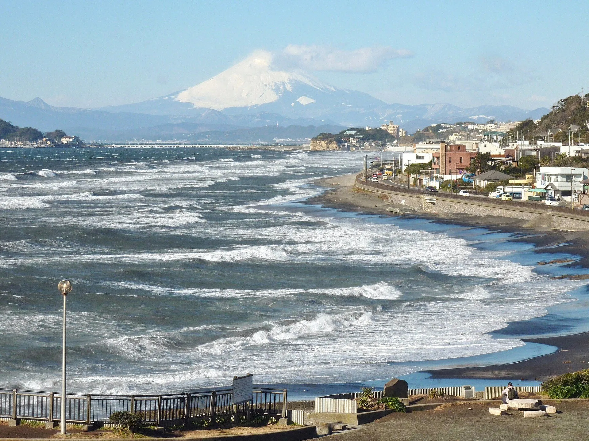 稲村ヶ崎の展望広場から西を望む。七里ヶ浜に白波が並び、その奥に雪をいただいた富士山がそびえる